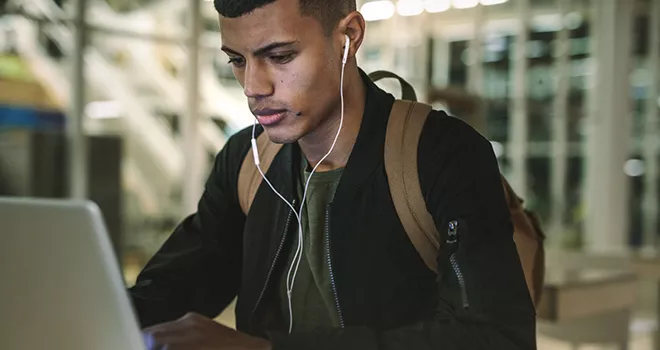 Young male student works at a laptop.