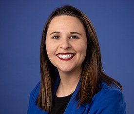 TCC Admission Counselor Lydia Mauldin smiles with long brown hair and black shirt with blue blazer.